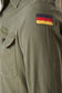 Green military-style uniform with a flag patch on the sleeve.